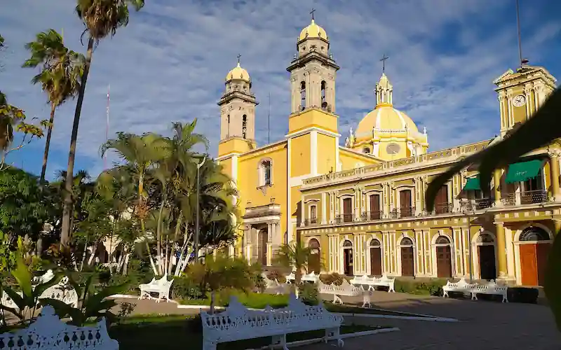 Fachada y torres amarillas de la Catedral Basilica Menor de Colima junto al parque principal.