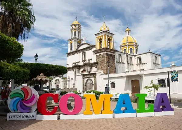 Letras monumentales de Comala con la Parroquia de San Miguel Arcángel de fondo.