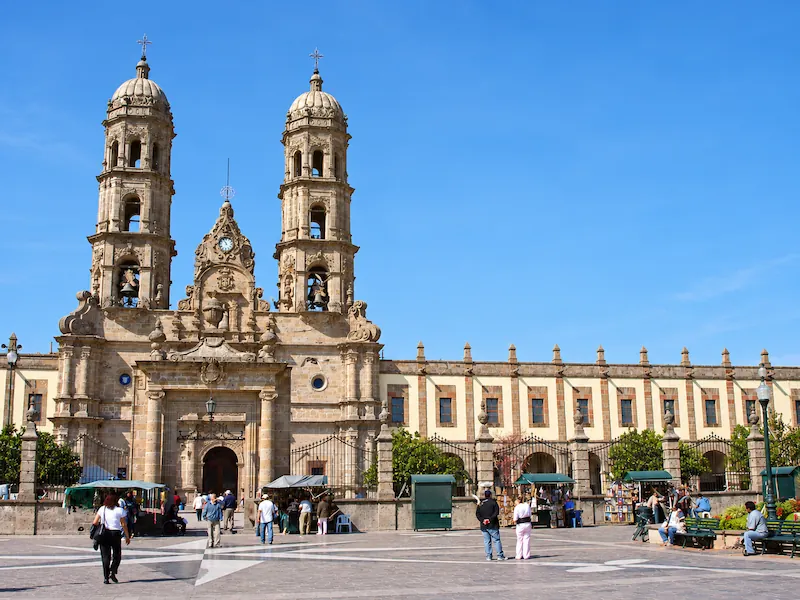 Vista frontal de las torres y fachada barroca de la Basílica de Zapopan frente a su explanada.