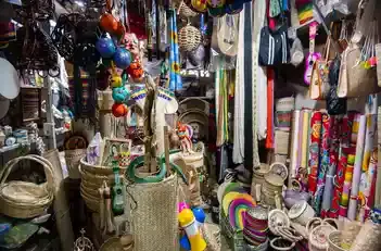 Puesto local en el mercado de artesanías repleto de canastas de mimbre, recuerdos y textiles coloridos.