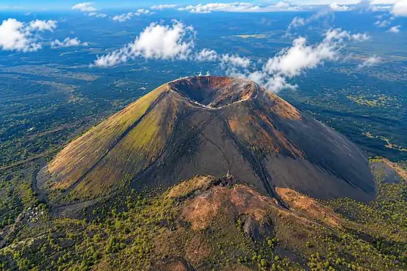 Vista aérea del cráter y cono volcánico del Parícutin rodeado de campos de lava y vegetación.