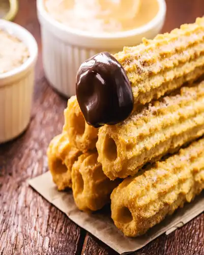 Torre de churros crujientes recién hechos cubiertos con chocolate frito y azúcar.