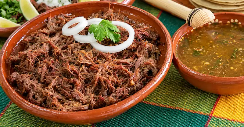 Barbacoa tradicional acompañada de tortillas y salsa
