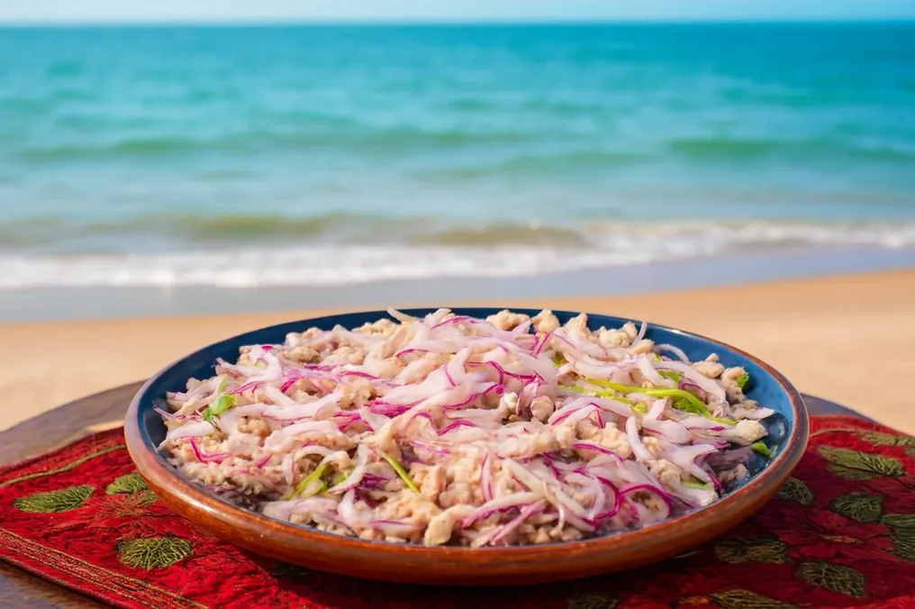 Plato con tiritas de pescado marinadas en limón con cebolla morada frente a la playa.