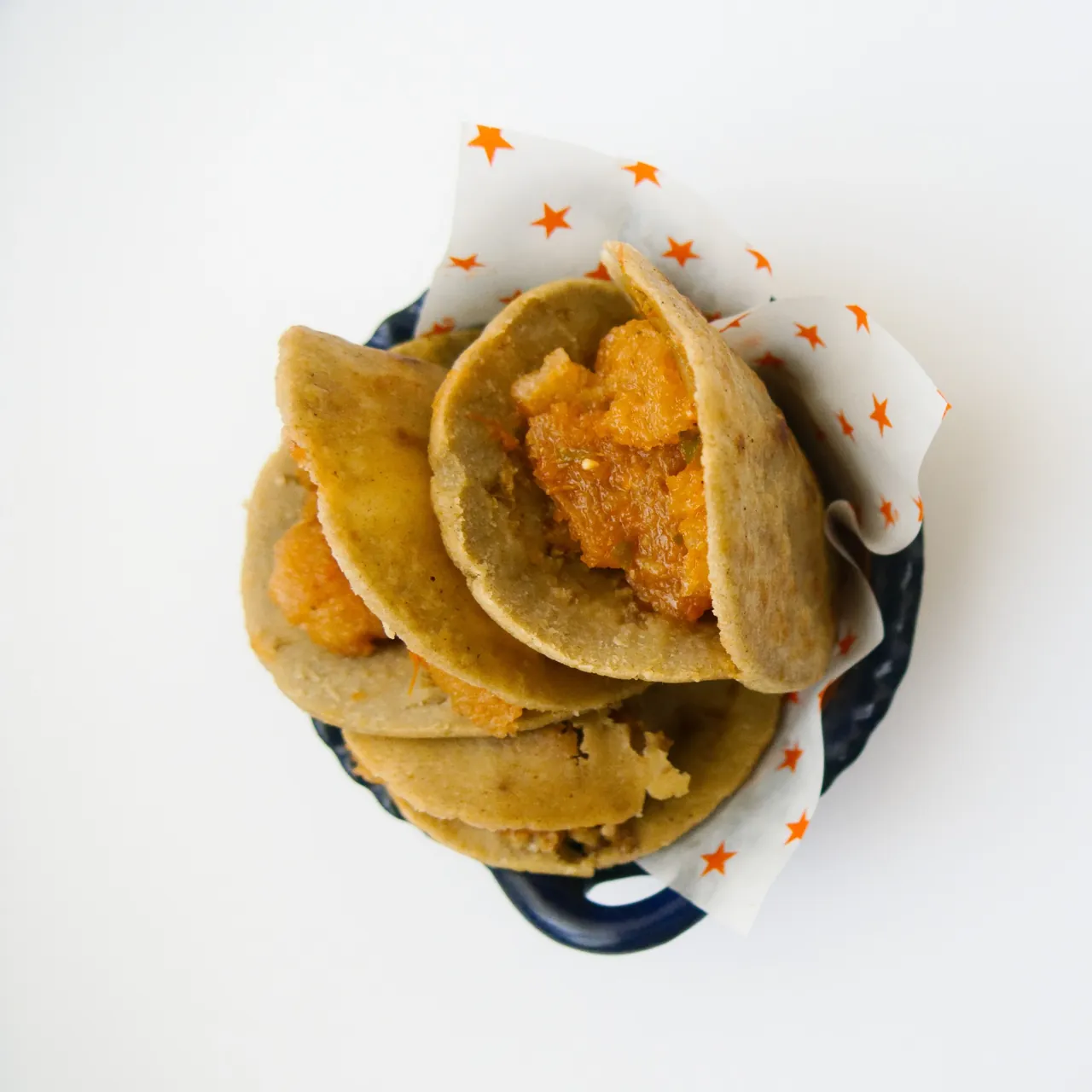 Cesta con gorditas de maíz quebradas rellenas de chicharrón prensado sobre papel decorativo.